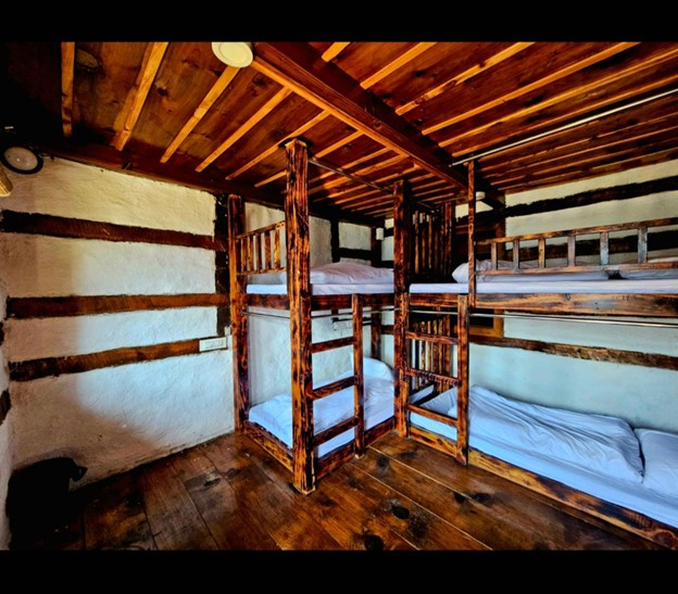 Parvati's Lap Hostel and Villa parvati valley, kasol, Himalayas - Classic wooden dorm room with strong Himachali architectural influence. Heavy timber beams and handcrafted bunk beds create a traditional mountain lodge atmosphere.